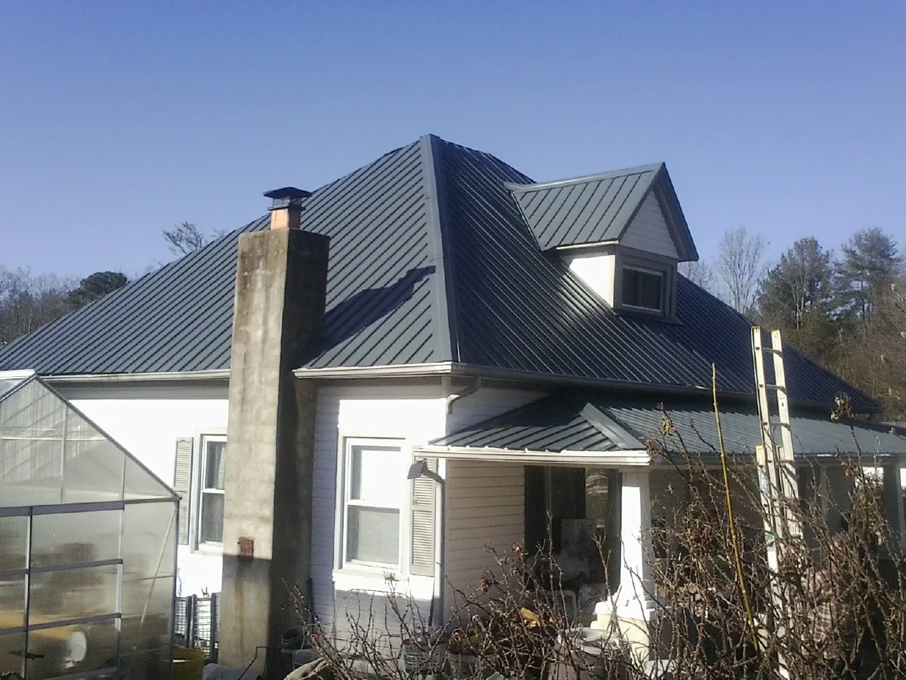 Dark blue standing seam metal roof on a white farmhouse with dormer — Slate & Tile Roof Repair by Roofing Brothers in Cle Elum
