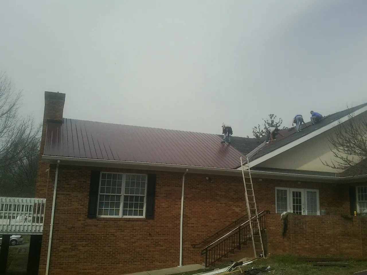 Crew setting red metal roofing panels on a brick home in Cle Elum