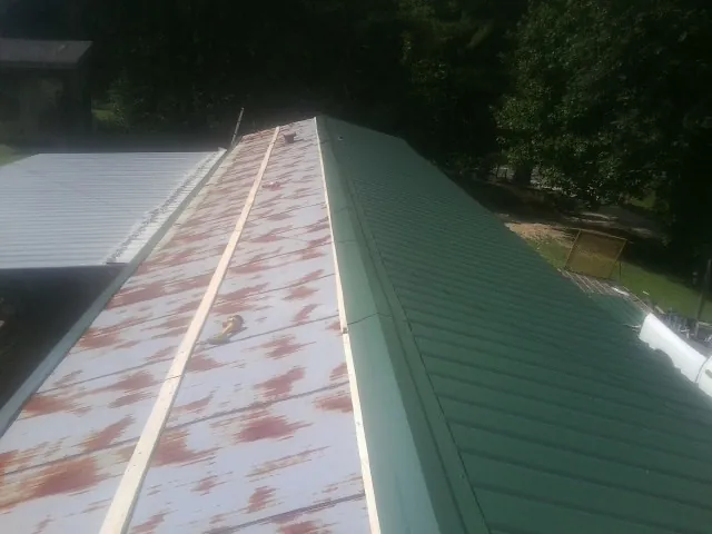 Old rusted panels beside newly installed green metal roofing — Wind Damage Roof Repair by Roofing Brothers in Cle Elum