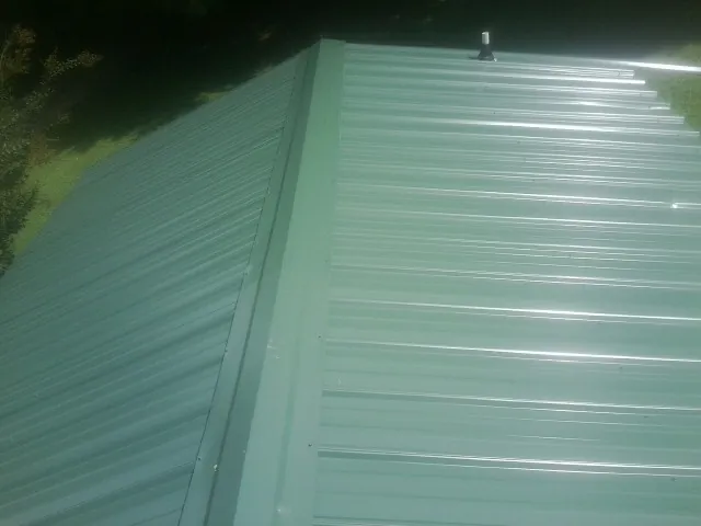 New green metal panels meeting at the ridge of a roof — Flat Roof Repair work by our crew in Cle Elum