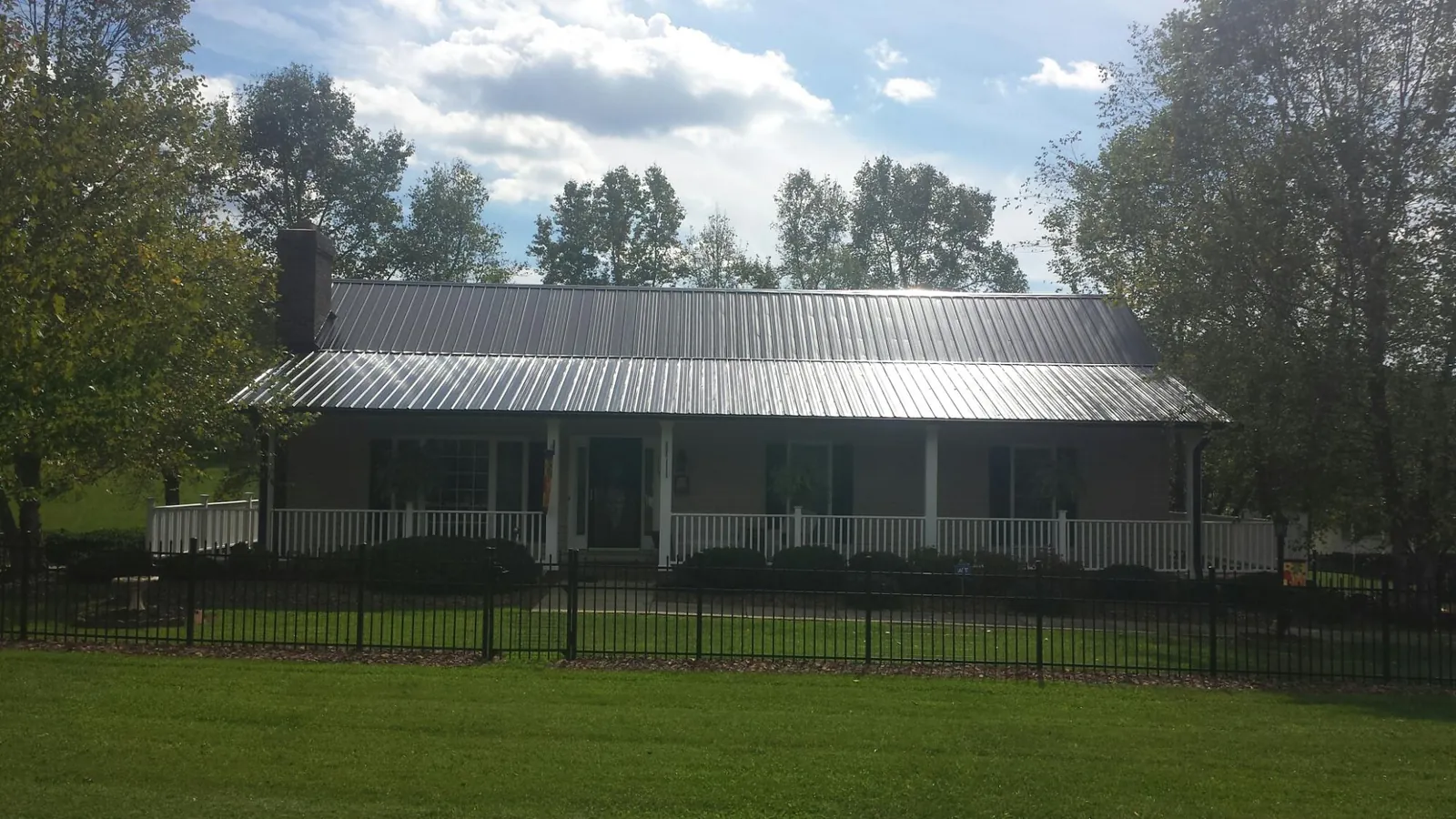 Gray metal roof on a brick ranch with a full width front porch — Gutter Guard Installation work by our crew in Cle Elum