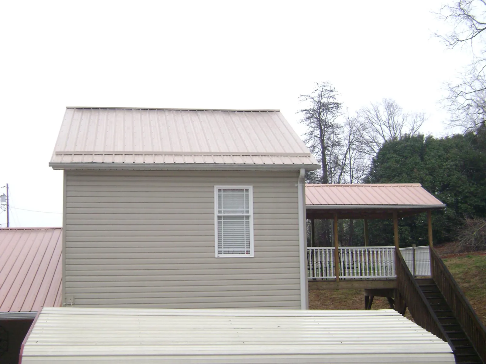 Tan metal roofs on a two story addition and attached porch, from a Roof Replacement job in Cle Elum