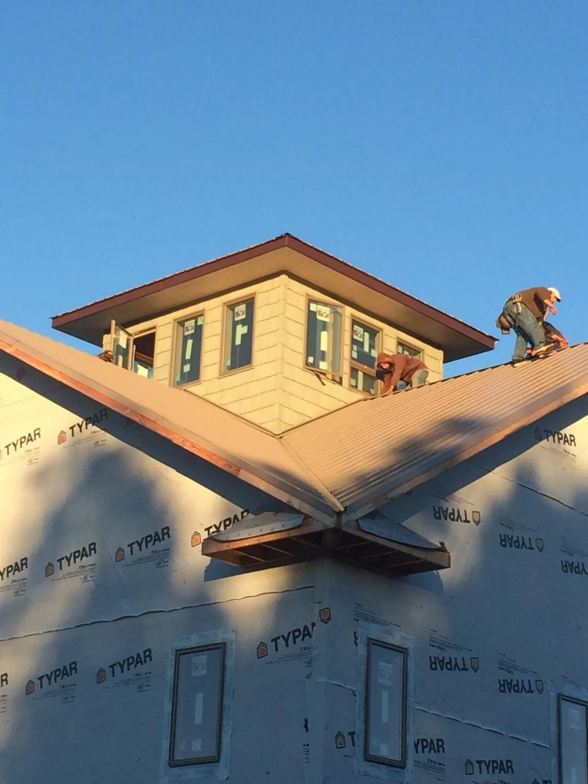 Roofers working around a rooftop cupola on a new metal roof at sunset — Roof Waterproofing in Cle Elum by Roofing Brothers